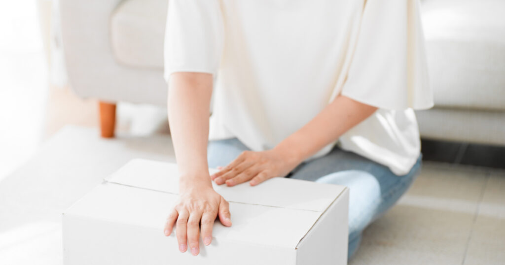 A woman is putting her luggage into a cardboard box